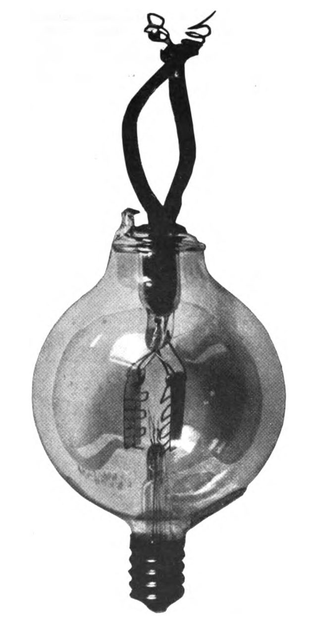 An early Audion tube: a round glass bulb about five centimetres across with its electrodes visible inside and wire leads twisted together at the top