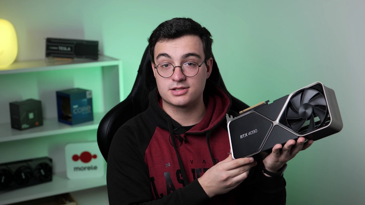 A man holding an RTX 4090 Founders Edition at chest height: a long silver and black card with a large fan