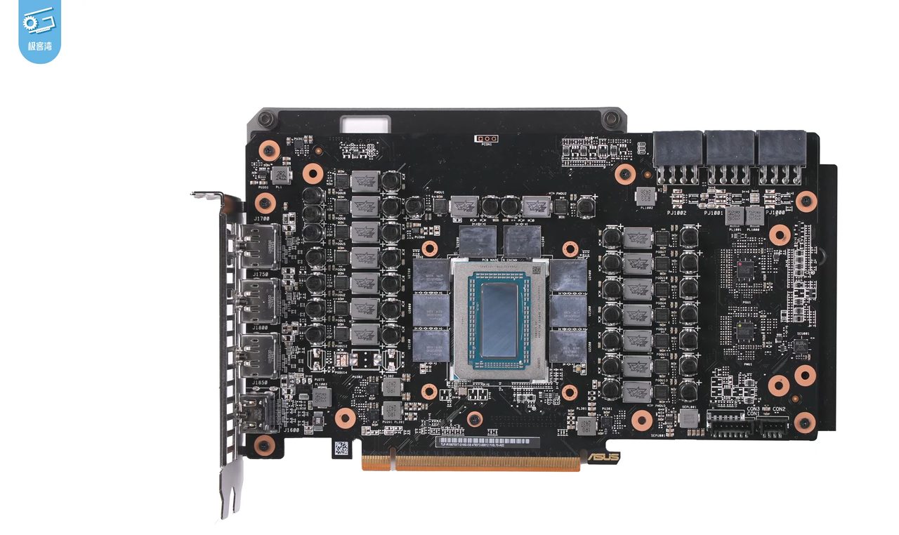 The circuit board of an ASUS Radeon RX 9070 XT with its cooler removed, on a white background: the shiny Navi 48 die in a metal frame in the centre, eight grey memory chips around it, columns of power components on either side, display connectors on the left bracket and the gold PCI Express edge connector along the bottom