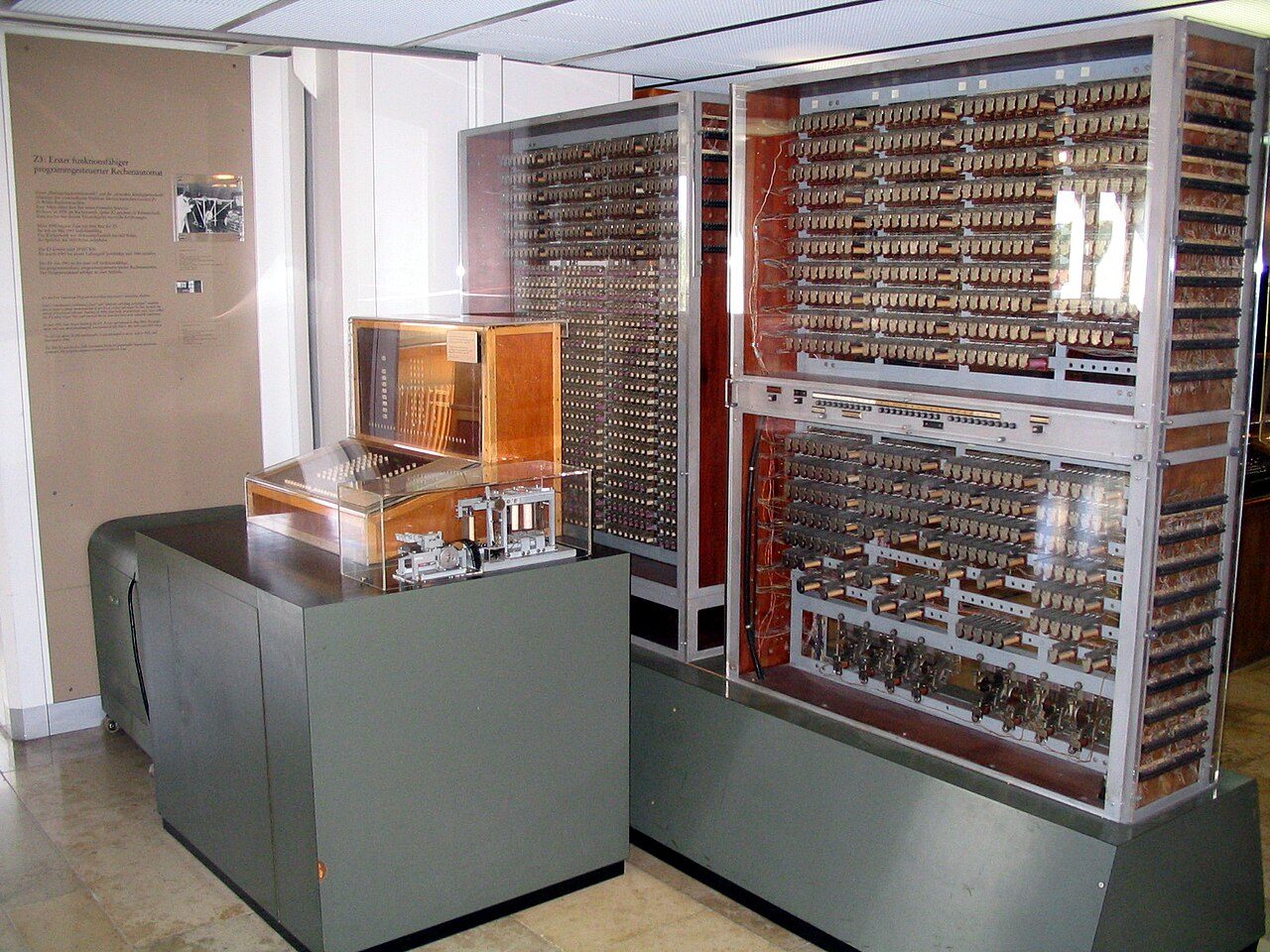 The Zuse Z3 replica in the Deutsches Museum: glass-fronted racks packed with rows of relays, with an operator's console on a table in front